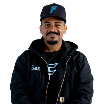 Man wearing black Flex Pest Control jacket and cap with logo, standing against white background.
