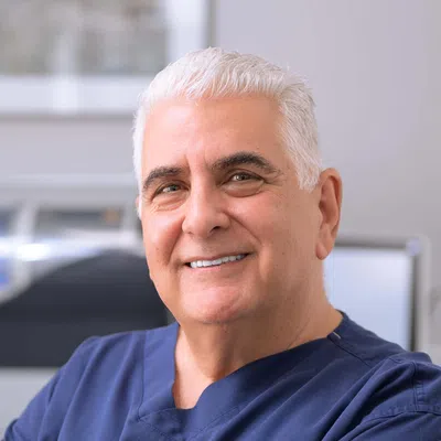 Smiling male dentist in navy uniform with Midland Park Family Dentistry logo in a bright dental office.