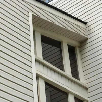 Close-up of beige modern house siding with large windows, showcasing architectural details and design elements.