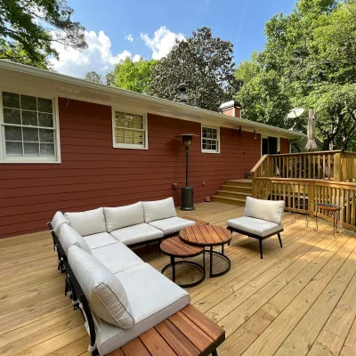 Red brick house exterior with brown window shutters and bushes under the windows on a sunny day