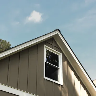 Close-up of a modern house roof and window with clear blue sky and surrounding trees on a sunny day