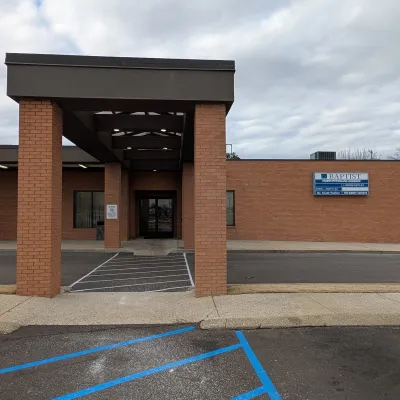 Entrance of a brick medical office building with covered walkway and handicap parking spaces under cloudy sky.