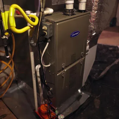 Residential Carrier furnace unit with pipes, wiring, and basement setup for heating and ventilation system.