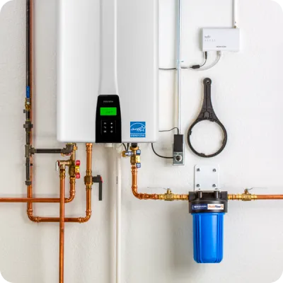 Modern tankless water heater installation with copper pipes and filtration system.