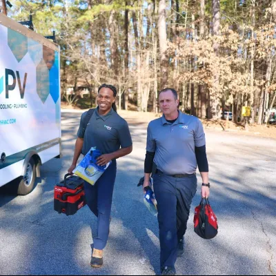 Two HVAC technicians walking towards a service van, ready for a job on a sunny day.