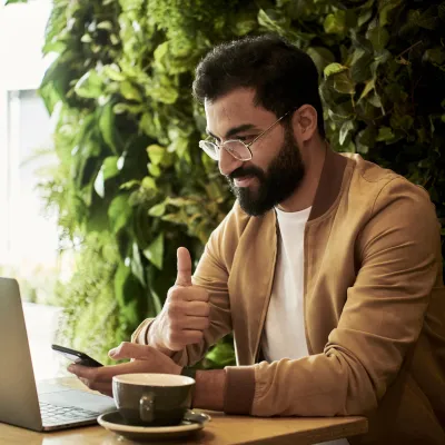 a man sitting at a table with a laptop and a cup of coffee