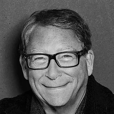 Black and white portrait of a smiling man with glasses against a plain background.