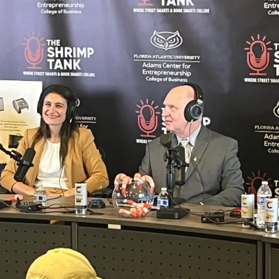 Two podcast hosts wearing headphones speaking into microphones during The Shrimp Tank event at Florida Atlantic University.