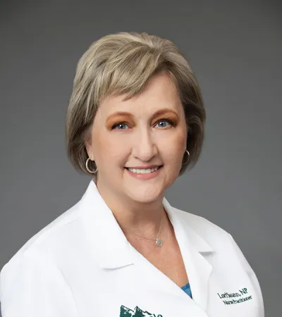 Female healthcare professional in a white coat with Pinnacle Orthopaedics logo smiling against gray background.