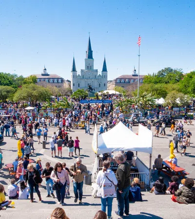 Crowd gathered at a lively outdoor event with St. Louis Cathedral in the background on a sunny day