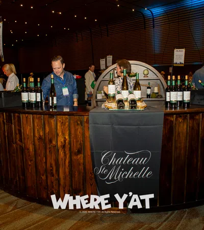 Wine tasting booth with Chateau Ste Michelle bottles and staff serving guests at indoor event
