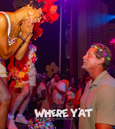 Energetic woman in floral outfit dances joyfully interacting with man wearing glowing flower crown at lively party.
