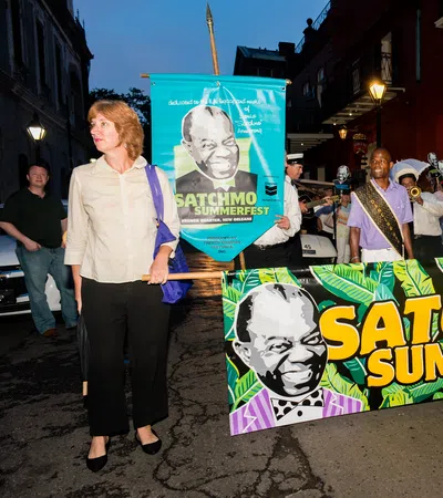People holding colorful banners for Satchmo Summerfest during an evening street parade in New Orleans.