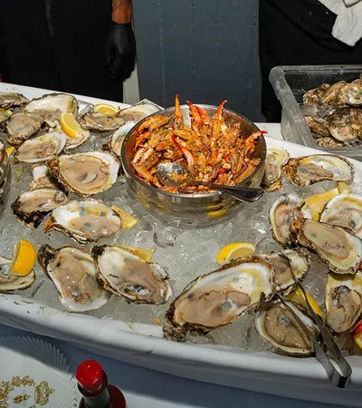 Seafood platter with fresh oysters, shrimp, crab legs, and lemon wedges served on ice at a buffet.