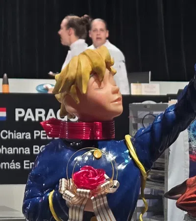 Colorful statue of a boy in blue holding a flower and a red rose with a fox looking up, Paraguay team banner in background