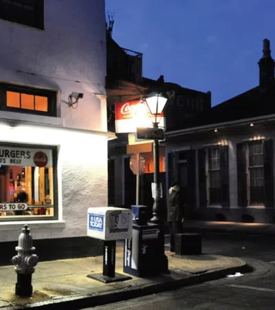 Night street scene with a brightly lit hamburger restaurant window and a nearby streetlamp illuminating the corner.