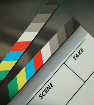 Hand holding a colorful film clapboard with sections for scene and take against blurred background