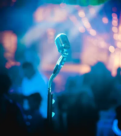 Vintage microphone on stage with blurred colorful concert crowd and lights in background