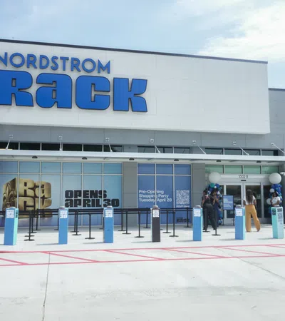 Nordstrom Rack store front with blue signage and people gathered outside for pre-opening event.
