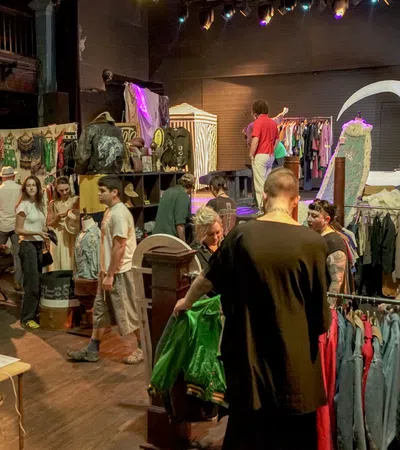 Busy indoor vintage clothing market with shoppers browsing racks and racks filled with colorful retro apparel.