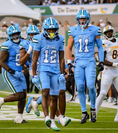 Tulane football players in blue uniforms celebrating on the field during a game against Southern University.