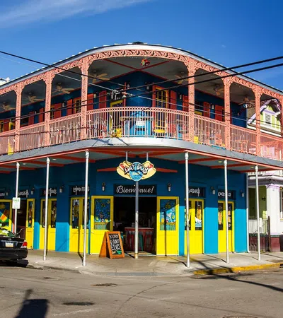 Colorful two-story building with yellow and blue walls and pink balcony railing at street corner in sunny weather