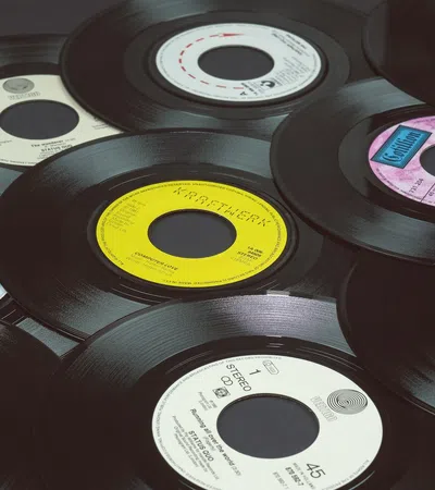 A collection of vintage 45 RPM vinyl records with colorful center labels overlapping on a flat surface.