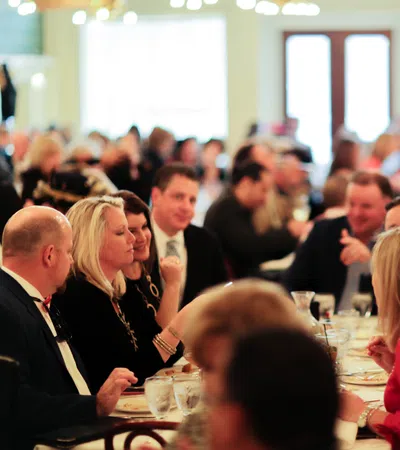 People enjoying a social gathering at a restaurant with conversations and dining in a warm, well-lit atmosphere.