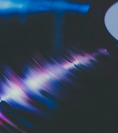 Close-up of a vinyl record spinning with colorful light reflections on its grooves in a dark setting