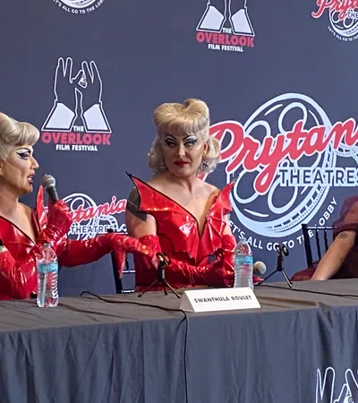 Two performers in red costumes speak at a panel with a moderator at Prytania Theatres for Overlook Film Festival.