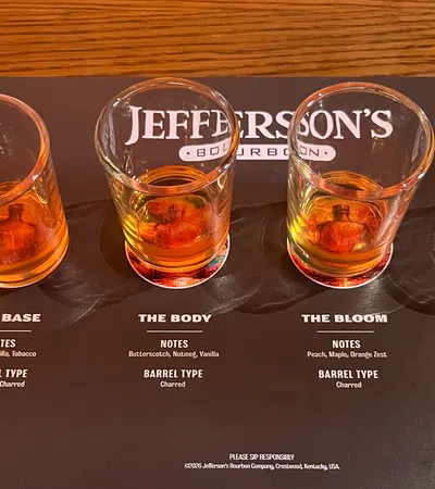 Four whiskey tasting glasses with varying bourbon samples on a Jefferson's Bourbon tasting mat showing flavor notes and barrel types.