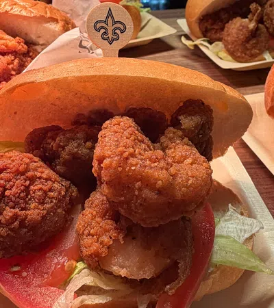 Close-up of fried shrimp po'boy sandwiches with lettuce and tomato on buns on wooden table