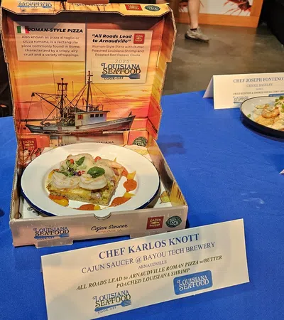 Gourmet seafood dishes displayed on a blue tablecloth with chef name cards at Louisiana Seafood event.