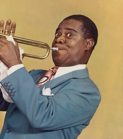 Man in blue suit playing trumpet with focused expression on yellow background.