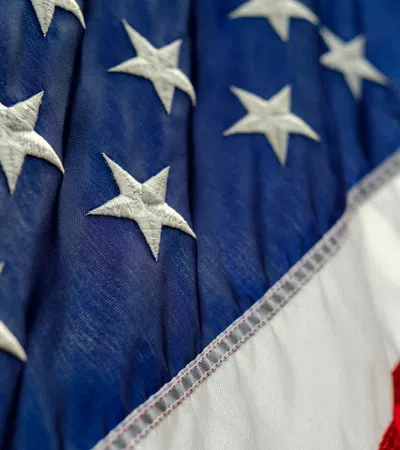 Close-up of the American flag showing white stars on blue fabric and part of red and white stripes.