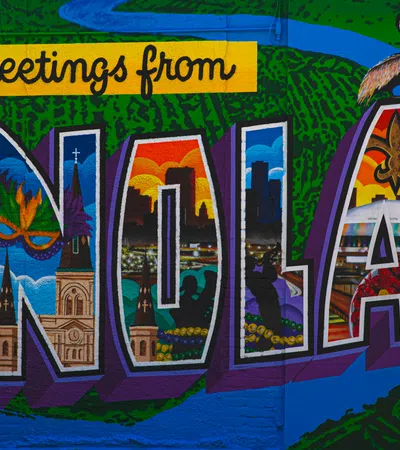 Colorful mural with Greetings from NOLA letters featuring New Orleans iconic landmarks and a pelican on top