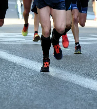 Close-up of runners' legs and feet in athletic shoes on a city road during a race event