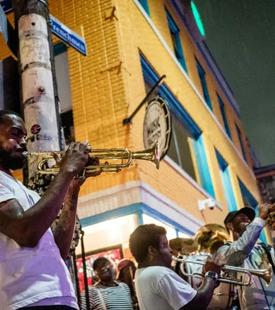 Street musicians playing trumpets and trombones during a lively outdoor jazz performance at night.