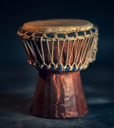 Close-up of a traditional wooden drum with rope tensioning on a dark background