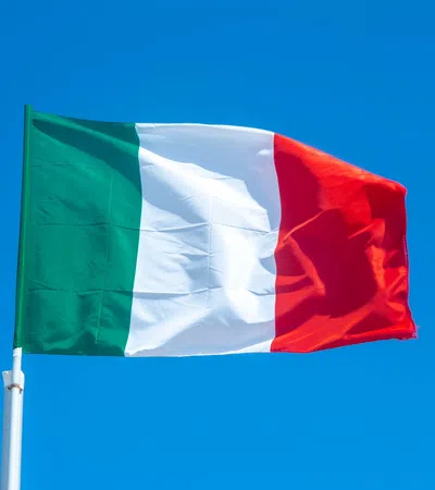 Italy national flag waving against a clear blue sky background outdoors.