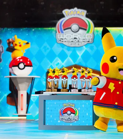 Pikachu mascot in red jacket poses near trophies at Pokémon World Championships in Anaheim 2022 event.