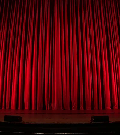 Closed red theater curtains illuminated on a stage ready for a performance.