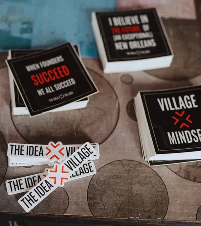 Stacks of motivational and branding stickers on a table featuring phrases like Village Mindset and The Idea Village.