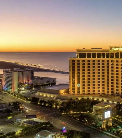 Beau Rivage casino resort lit at dusk with coastal view and colorful buildings along the shore.