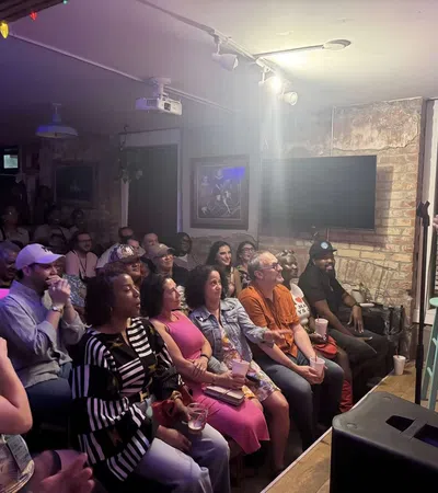 Crowd enjoying a live comedy show in a small venue with colorful lights and a performer on stage.