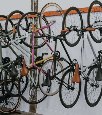 Multiple bicycles with leather seats hanging on wall racks and others parked on the floor in a bike shop.