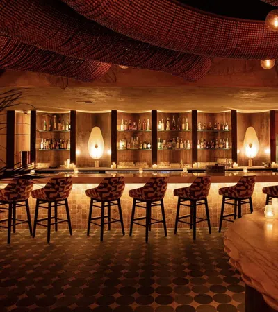 Cozy upscale bar with stylish patterned stools, warm ambient lighting, and a well-stocked liquor display.