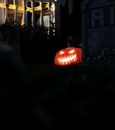 Glowing carved jack-o'-lantern beside a tombstone with RIP in a dark Halloween yard scene.