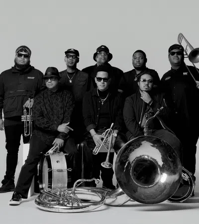Black and white photo of an eight-member brass band with instruments including trumpet, trombone, and drums.