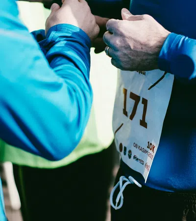 Runners adjusting race bib number 171 before a 10k event on a sunny day with blue athletic gear.